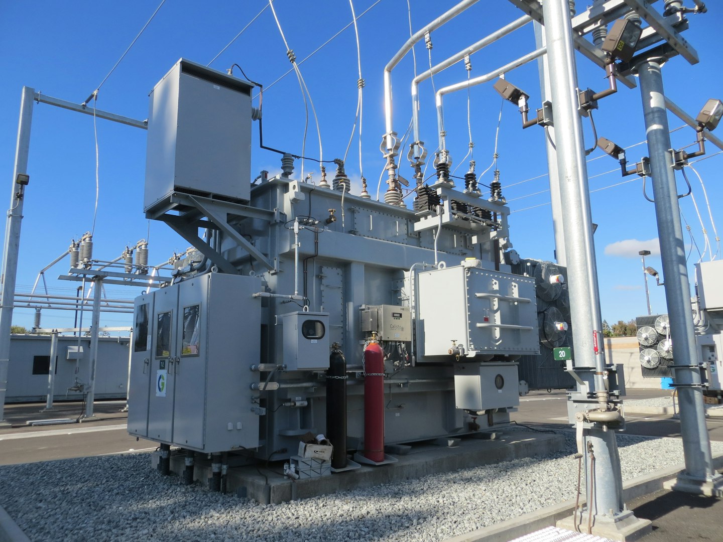 Transformator mocy w stacji elektroenergetycznej, nad nim odłączniki i przewody odciągowe