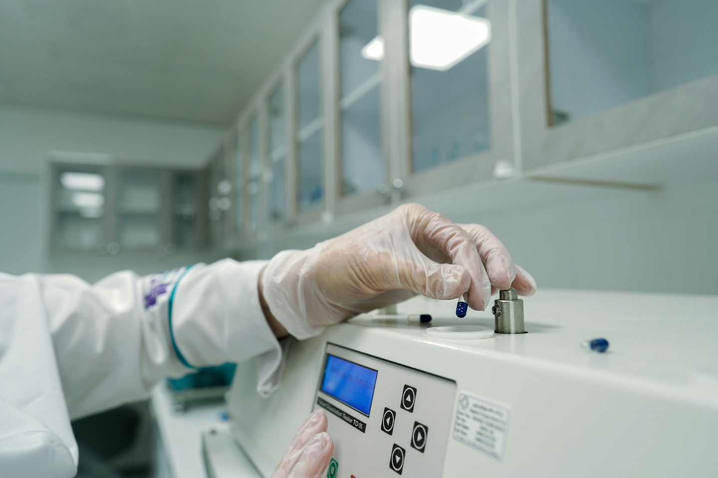 Dłonie w rękawiczkach obsługują aparaturę laboratoryjną